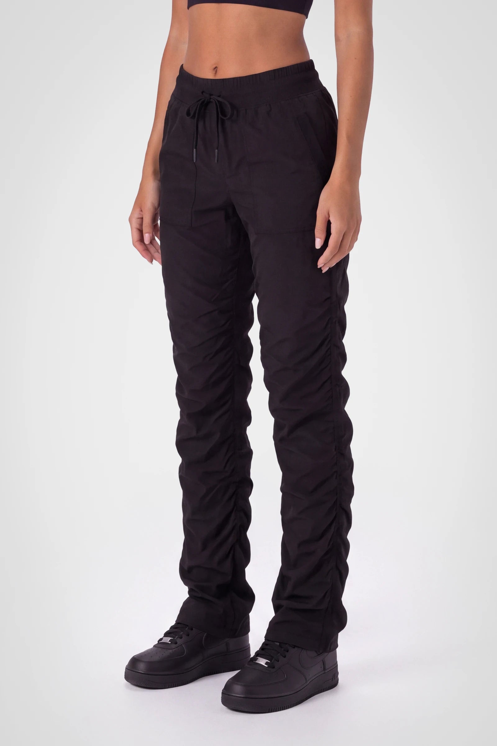 Women’s Black Adventurous Pant, side profile showing the drawstring waist, utility patch pocket and tapered leg.